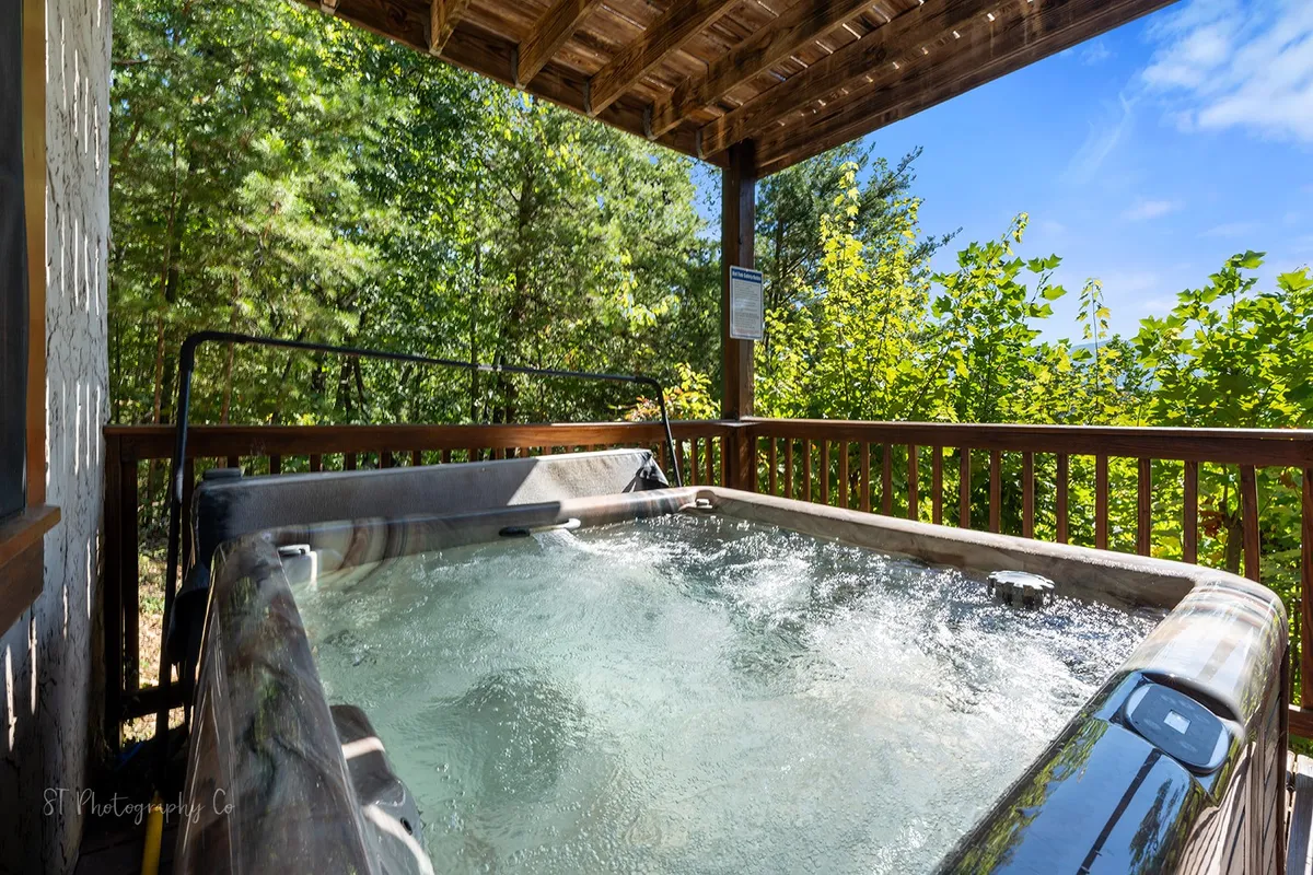 A wooden deck with a bubbling hot tub set against a backdrop of greenery. The hot tub overlooks the natural surroundings, creating an atmosphere of relaxation and connection with nature—perfect for unwinding after a day of team-building.