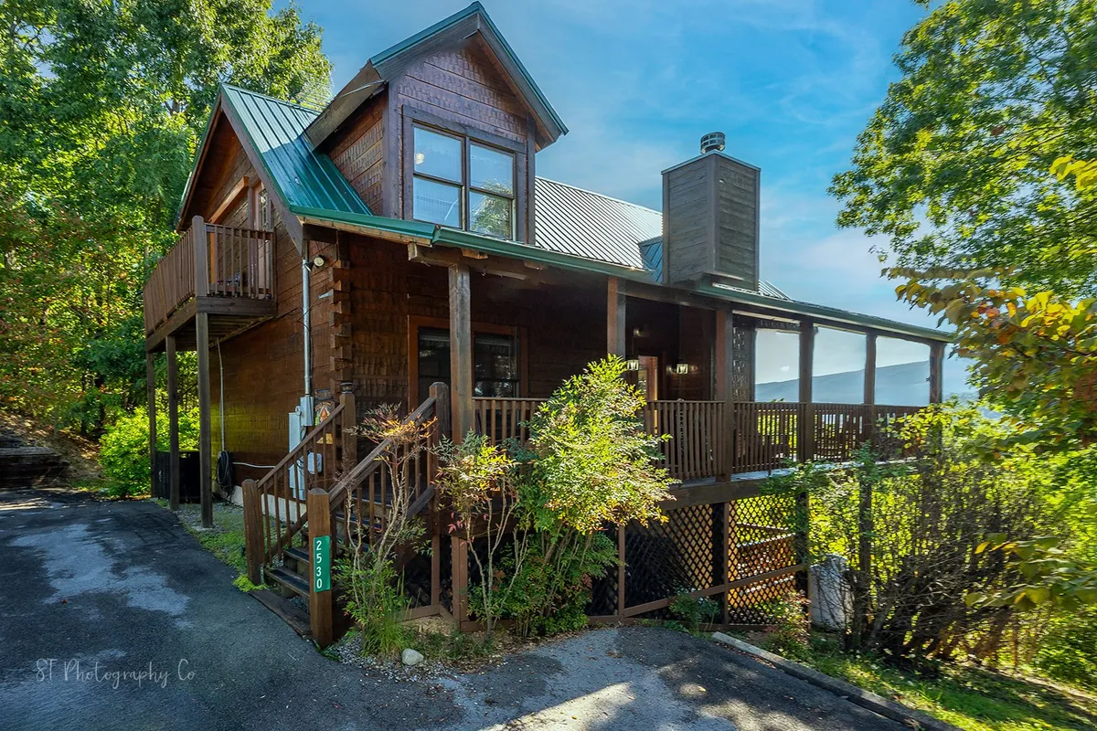 A welcoming wooden porch with a green roof and balcony surrounded by lush scenery. The view from the porch emphasizes the connection between indoor comfort and the natural world just outside, setting the stage for gatherings or quiet reflection across every season.