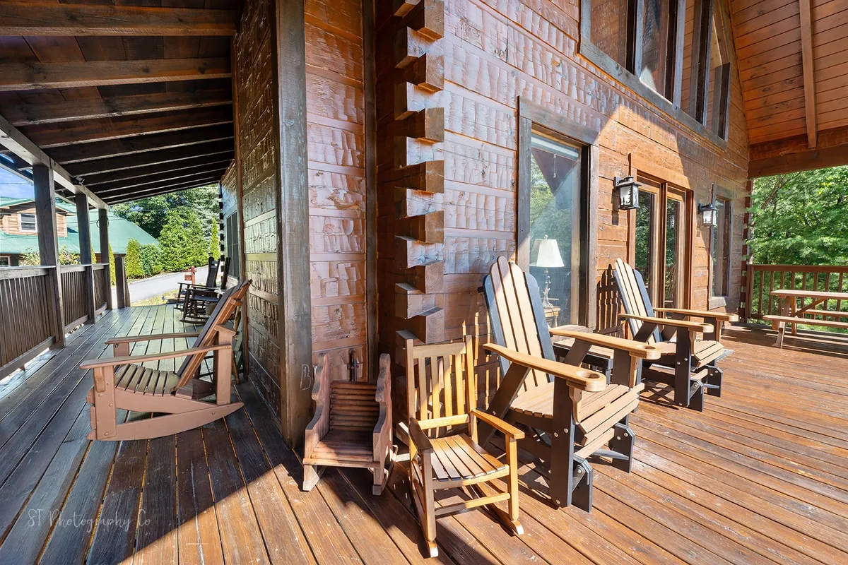 This image shows a spacious wooden deck adorned with classic rocking chairs, large windows of the cabin, and lush surrounding greenery. The scene is tranquil and inviting, suggesting an ideal space for teams to unwind, hold relaxed conversations, or enjoy nature together.